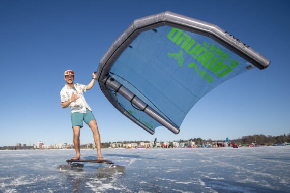 A person with a wingsail on ice in beach clothing