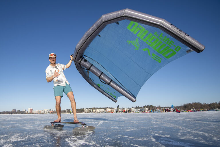 A person with a wingsail on ice in beach clothing