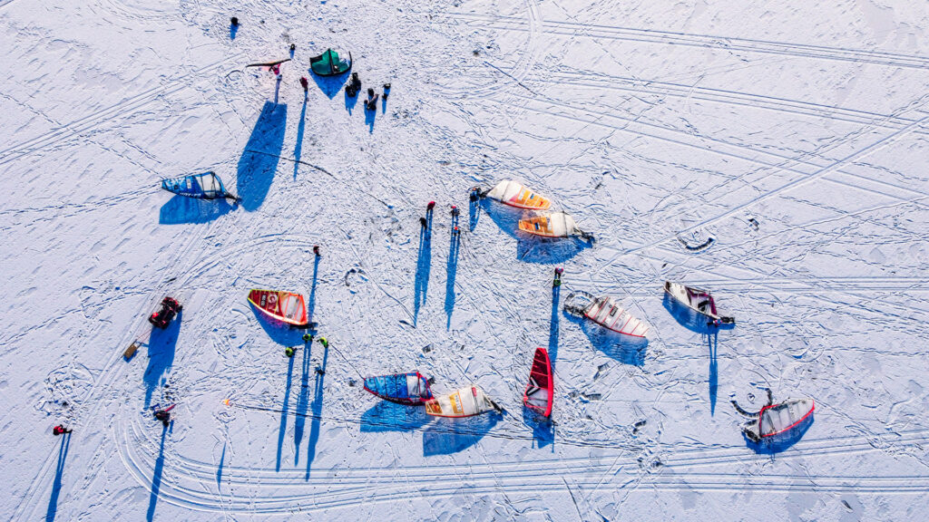 Drone view of sails and wings and people on the snowy ice